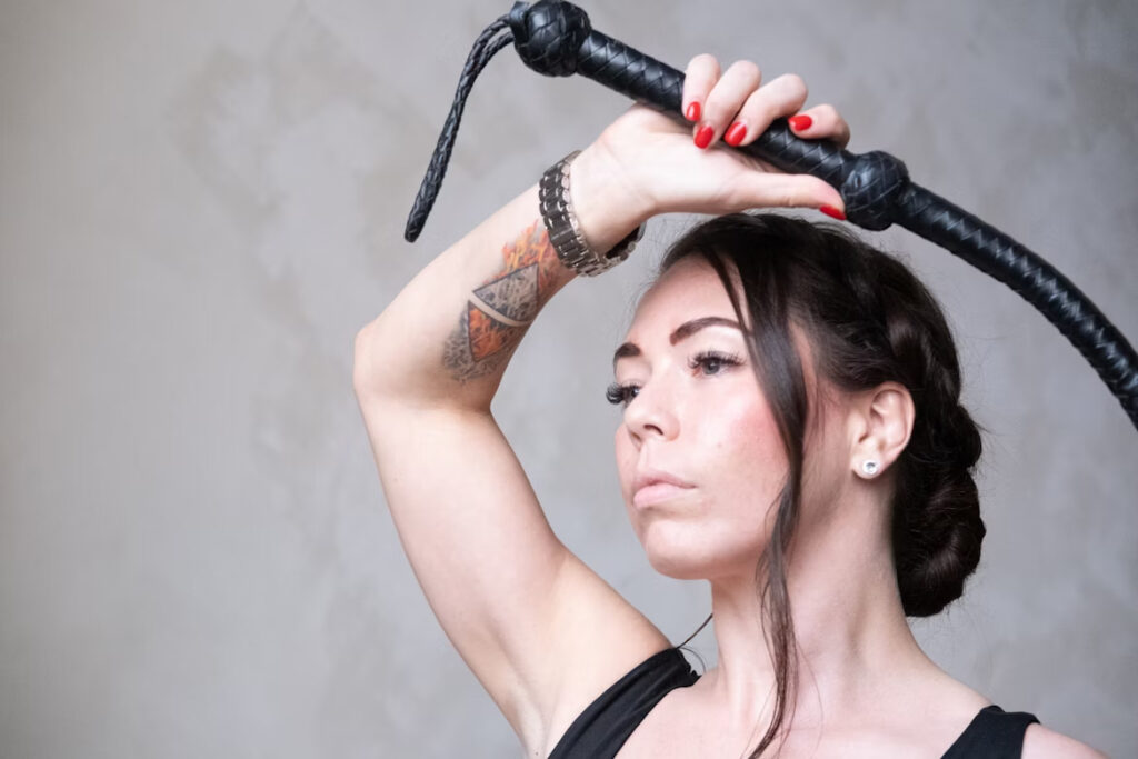 accessoire BDSM dominatrice tenant un fouet en cuir